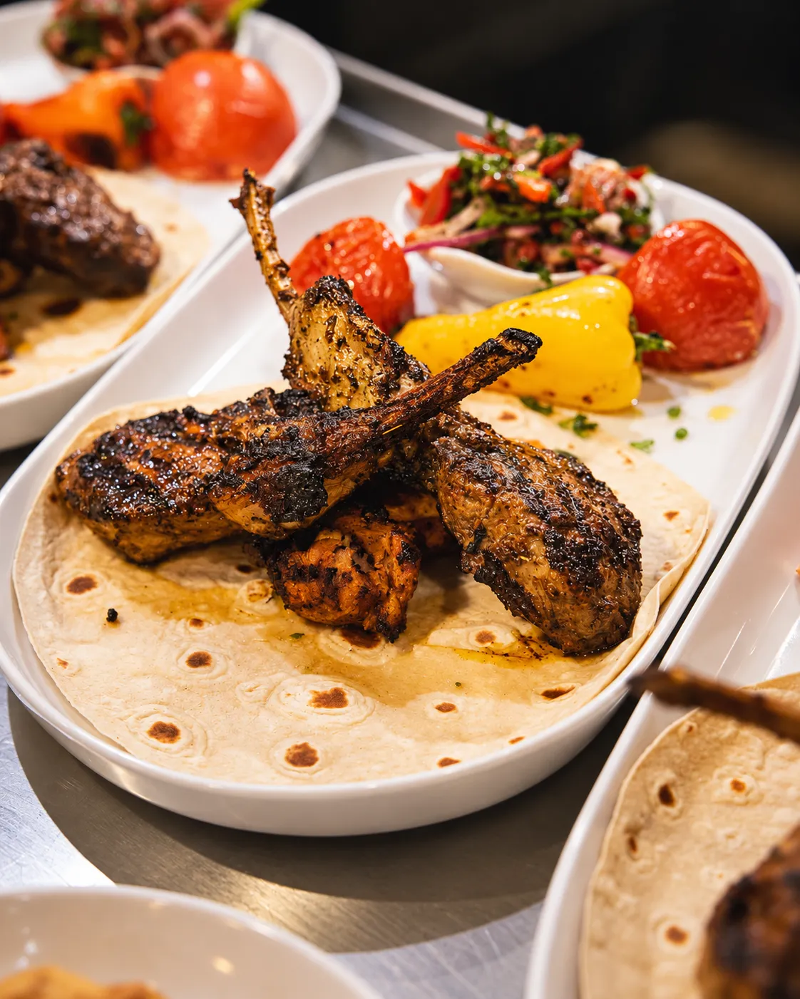 Grilled Mediterranean chicken skewers served on flatbread with roasted peppers and tomatoes